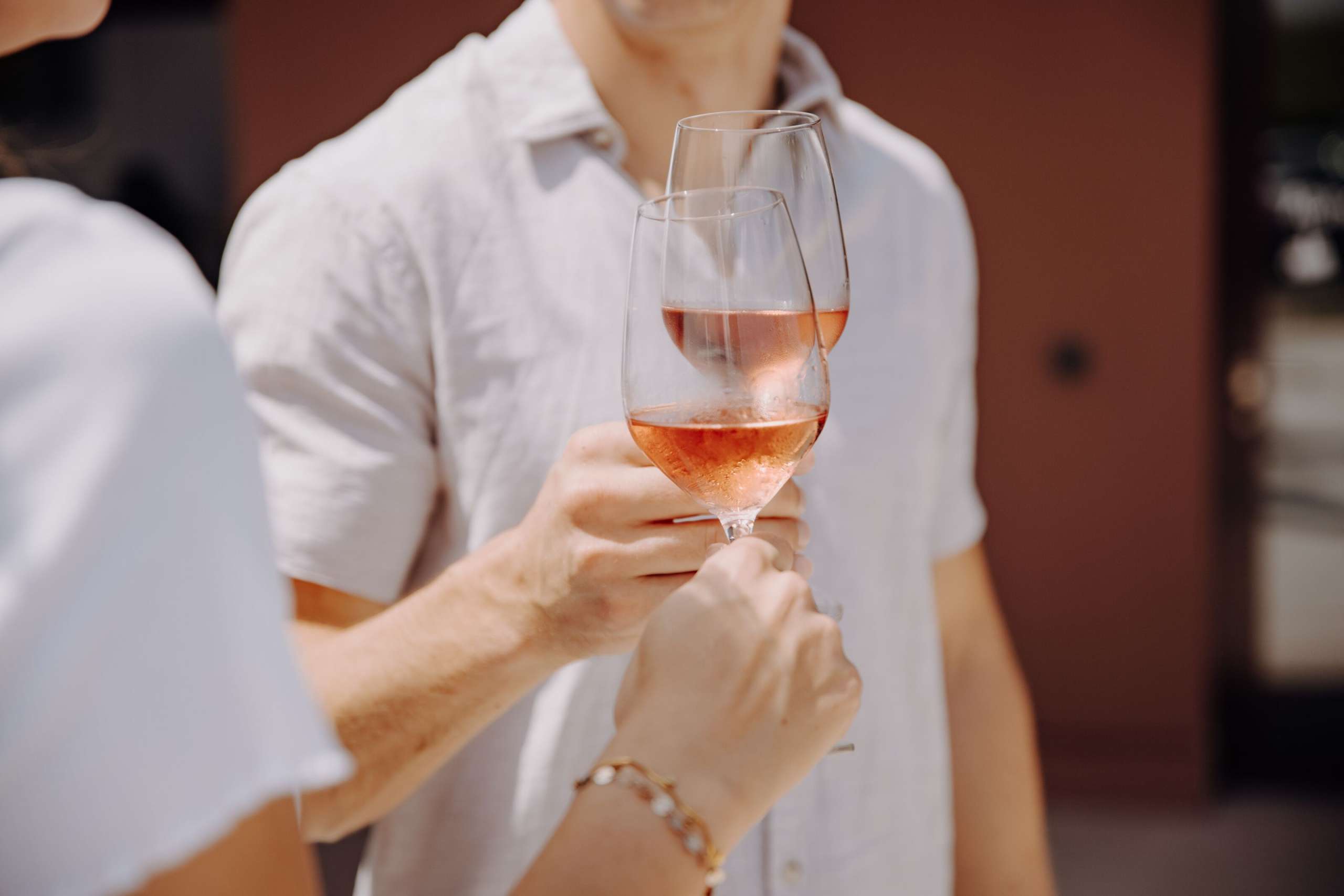 Zwei Personen stossen mit einem Glas Rosé an.