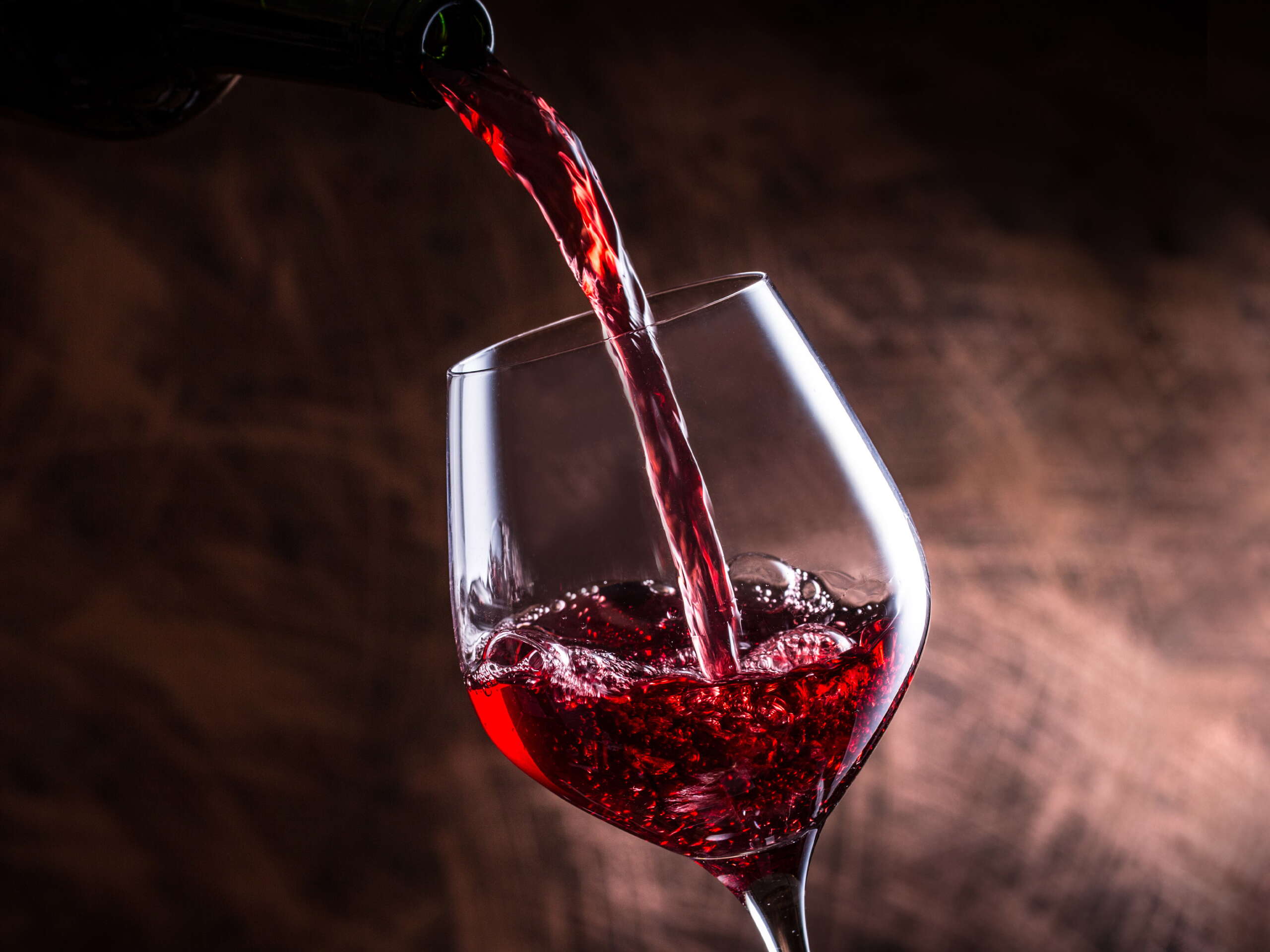 Ein Weinglas in das Rotwein eingeschenkt wird.
